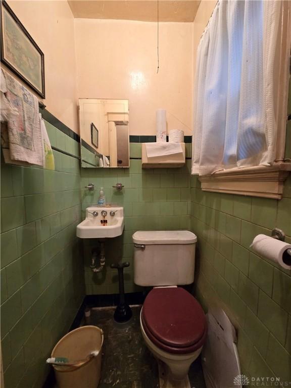 bathroom with tile walls, sink, and toilet