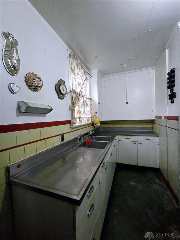 kitchen featuring white cabinets, sink, and tile walls