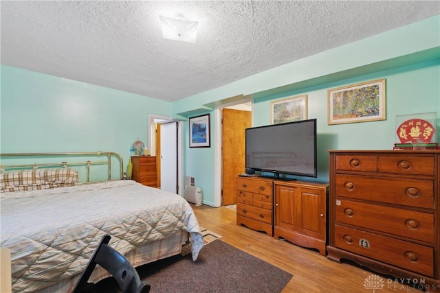 bedroom featuring light hardwood / wood-style floors and a textured ceiling