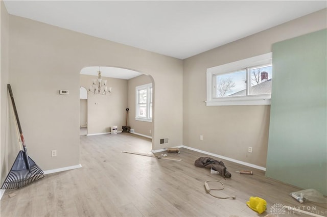 empty room featuring light wood-type flooring and an inviting chandelier