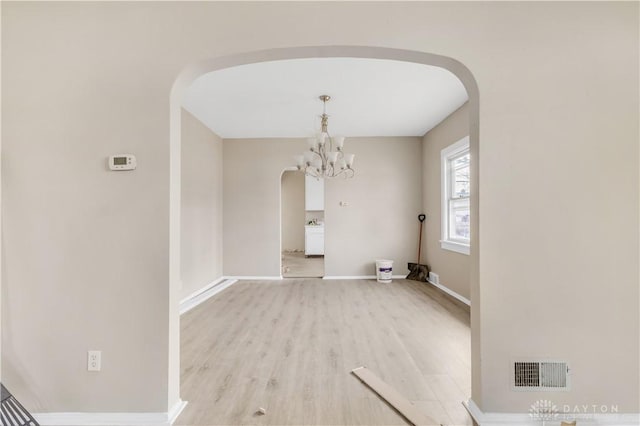 unfurnished dining area featuring light hardwood / wood-style floors and a notable chandelier