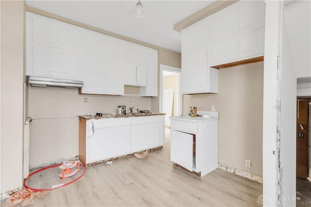 kitchen with light wood-type flooring and white cabinetry