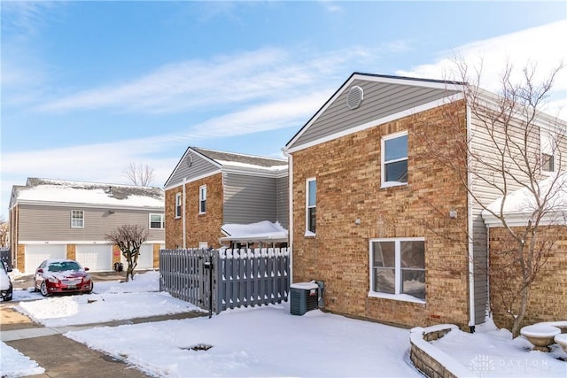 exterior space with central AC, brick siding, and fence