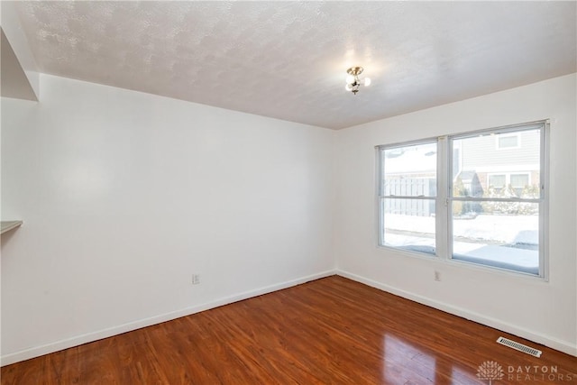 spare room with a textured ceiling and hardwood / wood-style flooring