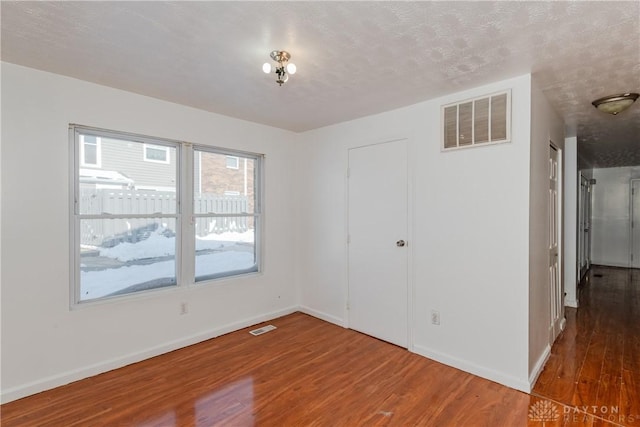 empty room with a textured ceiling and hardwood / wood-style floors