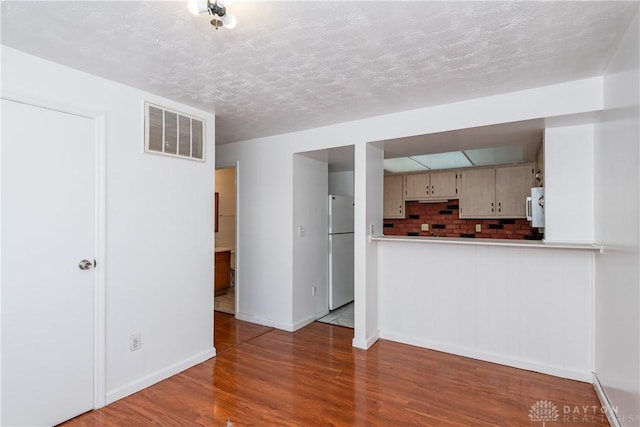 unfurnished living room featuring a textured ceiling and wood-type flooring