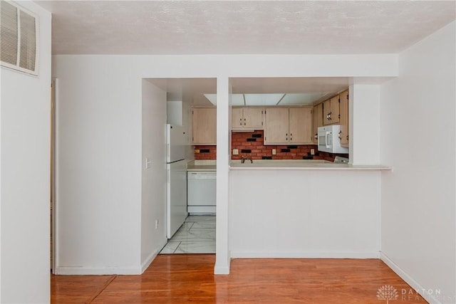 kitchen featuring light wood-type flooring, cream cabinets, white appliances, a textured ceiling, and decorative backsplash