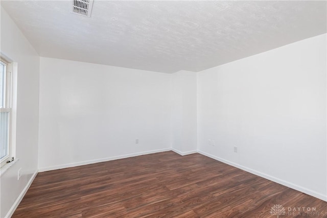 spare room featuring dark hardwood / wood-style flooring and a textured ceiling