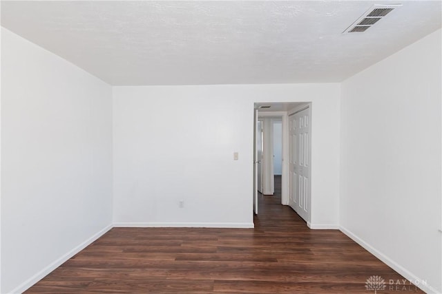 empty room with a textured ceiling and dark wood-type flooring