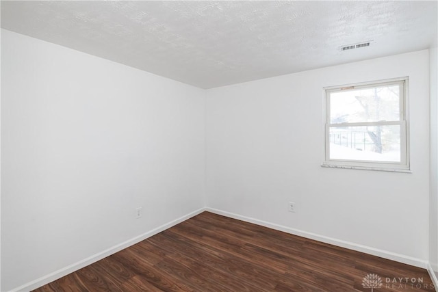 unfurnished room with dark wood-type flooring and a textured ceiling