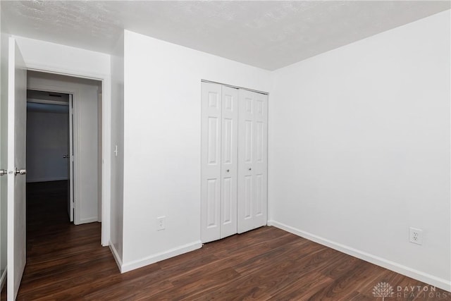 unfurnished bedroom featuring a closet and dark hardwood / wood-style floors