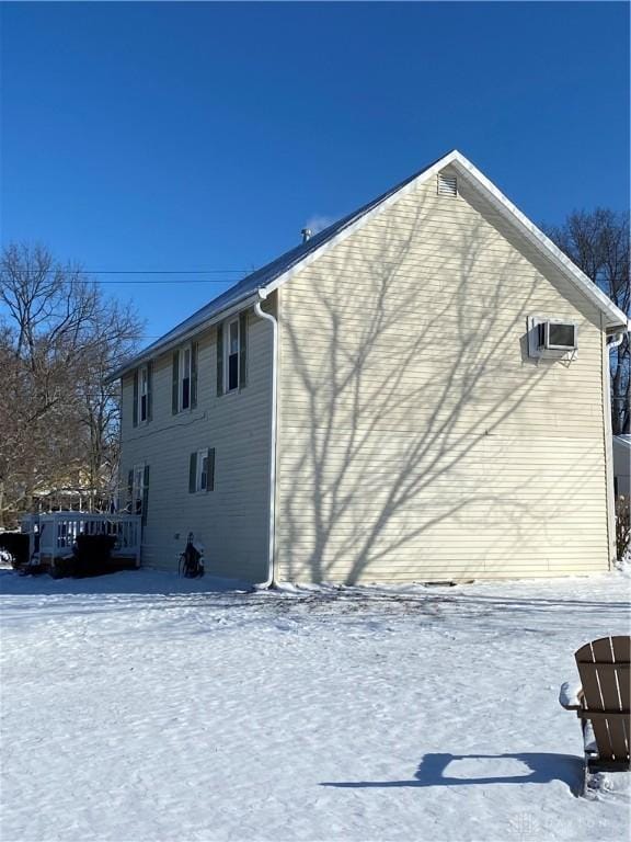 snow covered property with a wall mounted air conditioner