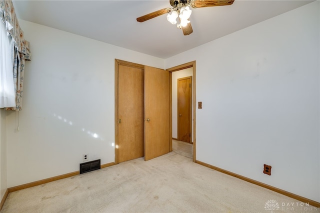 unfurnished bedroom with ceiling fan, light carpet, and a closet