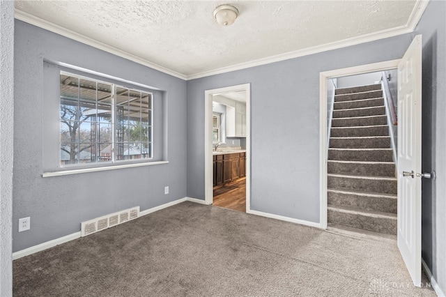 unfurnished bedroom featuring carpet floors, ornamental molding, ensuite bathroom, and a textured ceiling