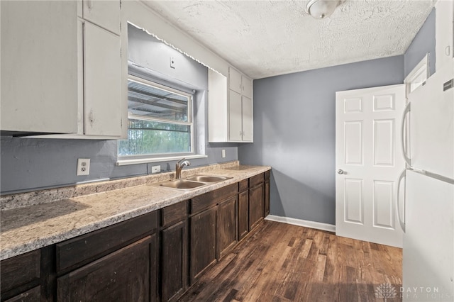 kitchen with white fridge, sink, white cabinetry, a textured ceiling, and dark hardwood / wood-style flooring