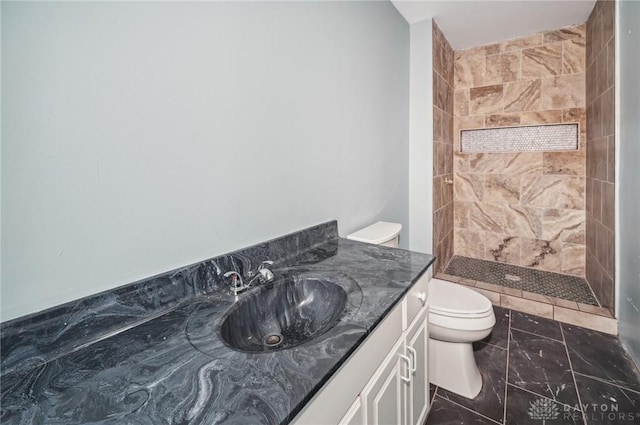 bathroom with vanity, a tile shower, and toilet