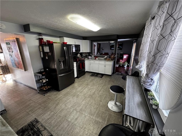 kitchen with white cabinetry, black appliances, and a textured ceiling