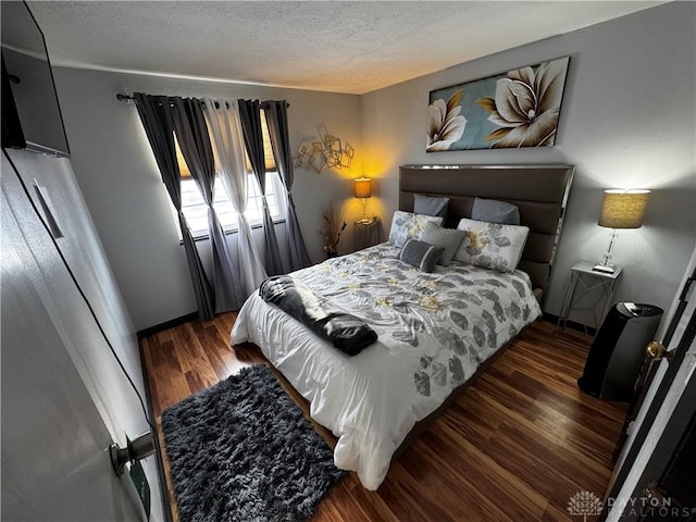 bedroom with a textured ceiling and dark hardwood / wood-style floors