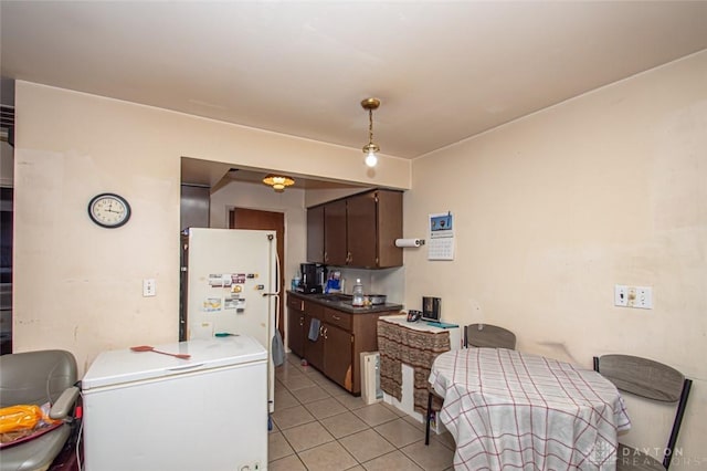 kitchen with light tile patterned floors, fridge, dark brown cabinets, and white refrigerator