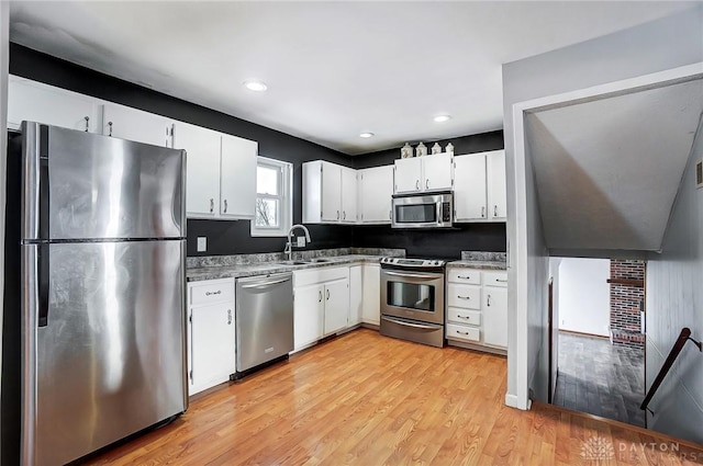 kitchen featuring sink, white cabinets, stainless steel appliances, and light hardwood / wood-style flooring