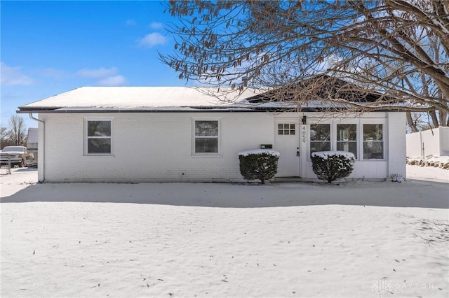 snow covered back of property with brick siding