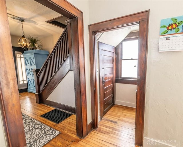 stairs with an inviting chandelier and hardwood / wood-style flooring