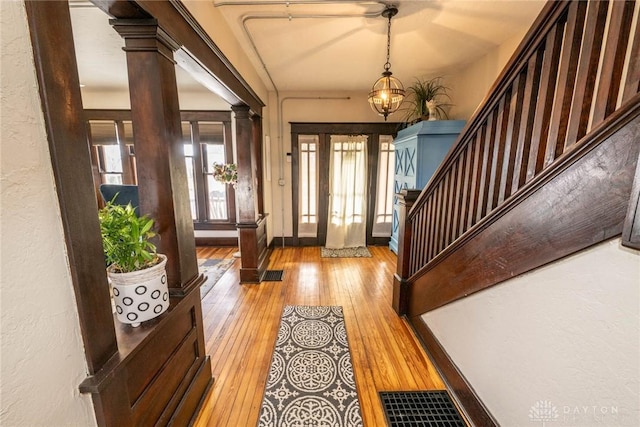 foyer entrance featuring ornate columns and light hardwood / wood-style flooring