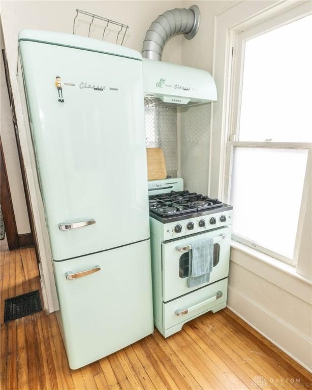 kitchen featuring white appliances, a healthy amount of sunlight, and light hardwood / wood-style flooring