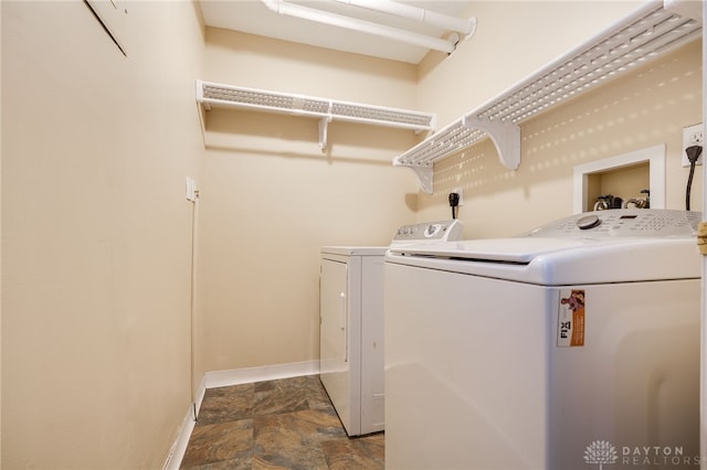 washroom with laundry area, stone finish floor, washer and clothes dryer, and baseboards