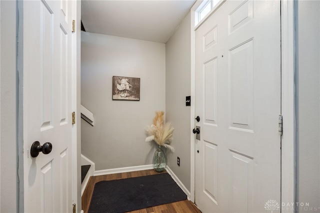 doorway to outside featuring baseboards and wood finished floors