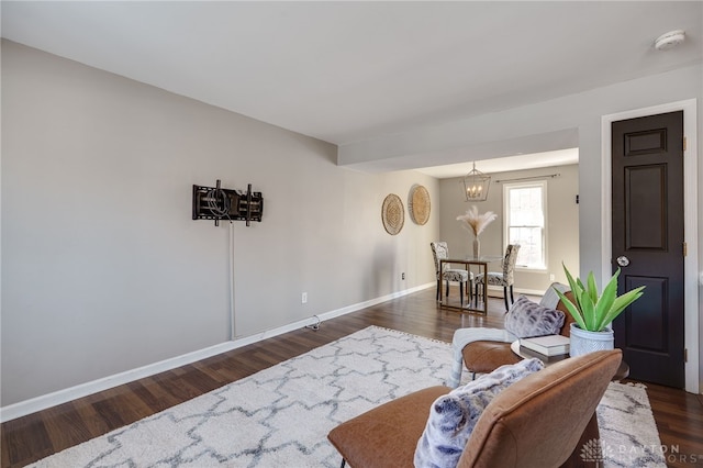 living room featuring dark wood-style flooring, a notable chandelier, and baseboards