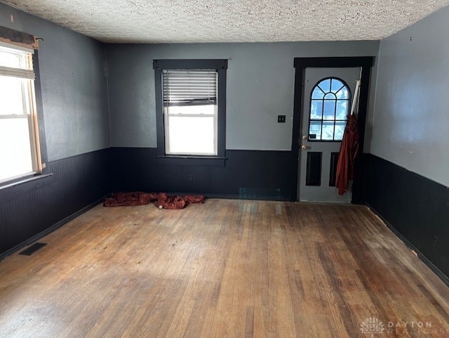 foyer featuring a textured ceiling, hardwood / wood-style floors, and wooden walls