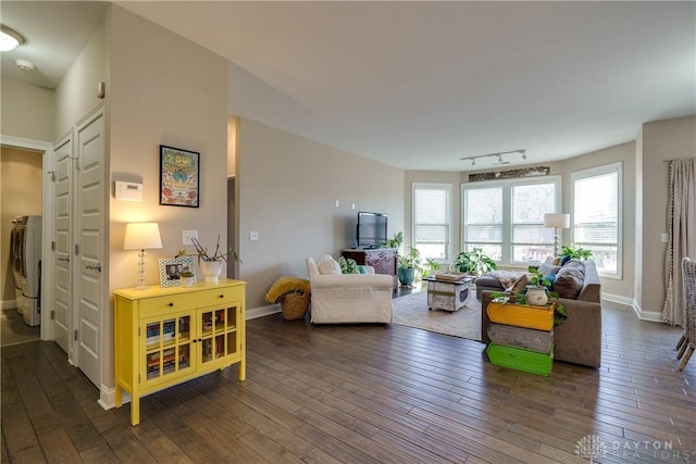 living room with rail lighting, washing machine and dryer, and dark hardwood / wood-style floors