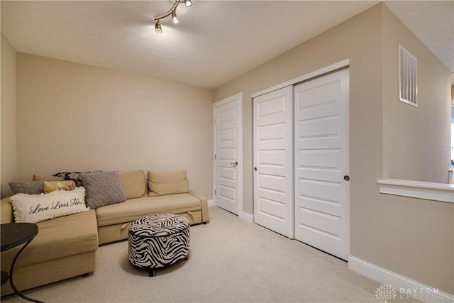 carpeted living room with a textured ceiling and track lighting