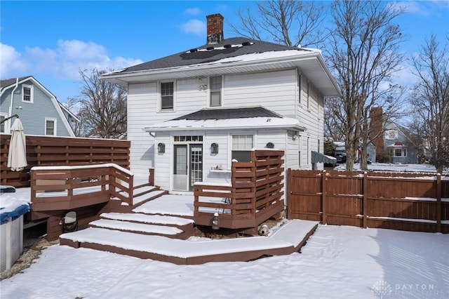 snow covered back of property featuring a deck