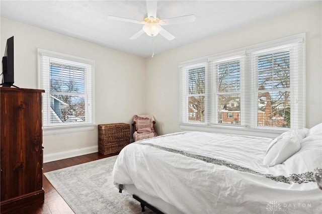 bedroom with ceiling fan, dark wood-type flooring, and multiple windows