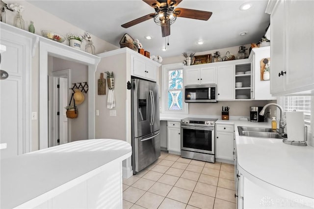 kitchen with stainless steel appliances, ceiling fan, light tile patterned floors, sink, and white cabinetry