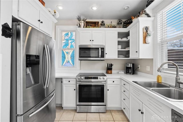 kitchen with appliances with stainless steel finishes, plenty of natural light, sink, and white cabinets