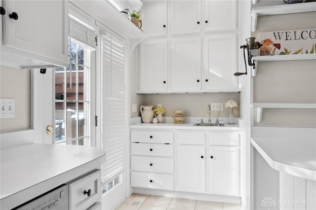 kitchen with white dishwasher, sink, white cabinetry, and light tile patterned floors