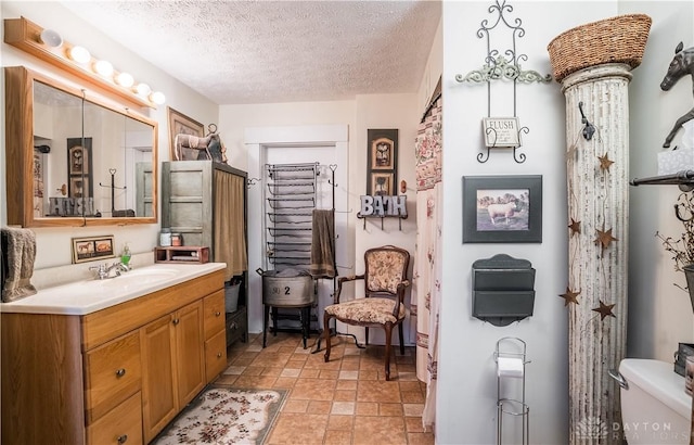 bathroom featuring a textured ceiling, toilet, and vanity