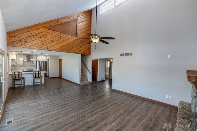 unfurnished living room with a high ceiling, ceiling fan, sink, and dark hardwood / wood-style flooring