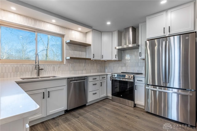 kitchen featuring wall chimney range hood, stainless steel appliances, white cabinets, and sink