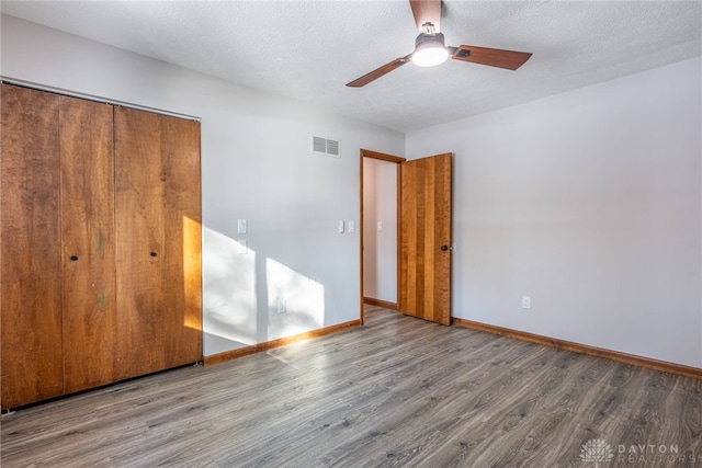 unfurnished bedroom with hardwood / wood-style floors, a closet, ceiling fan, and a textured ceiling