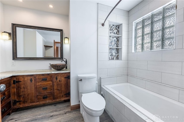 full bathroom with hardwood / wood-style flooring, toilet, vanity, and tiled shower / bath combo