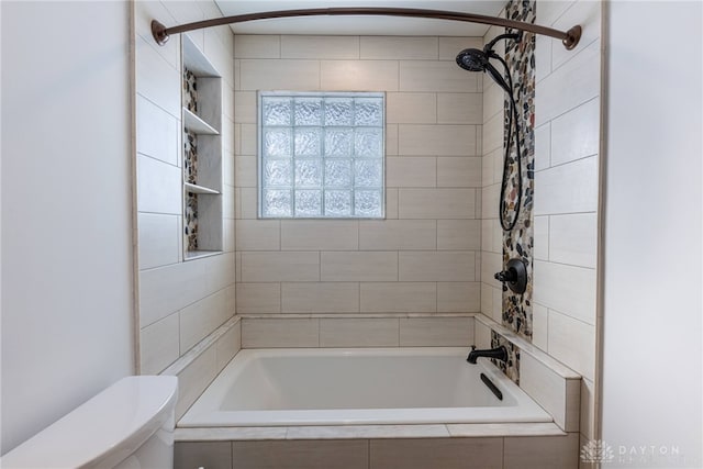 bathroom featuring toilet and tiled shower / bath