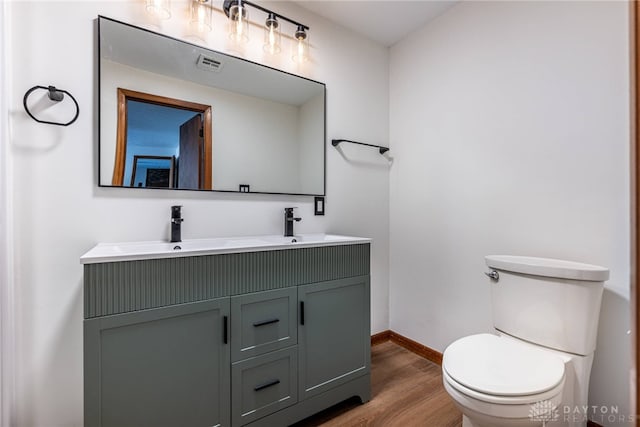 bathroom with toilet, vanity, and wood-type flooring