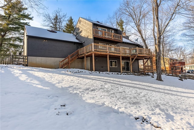 snow covered back of property featuring a deck