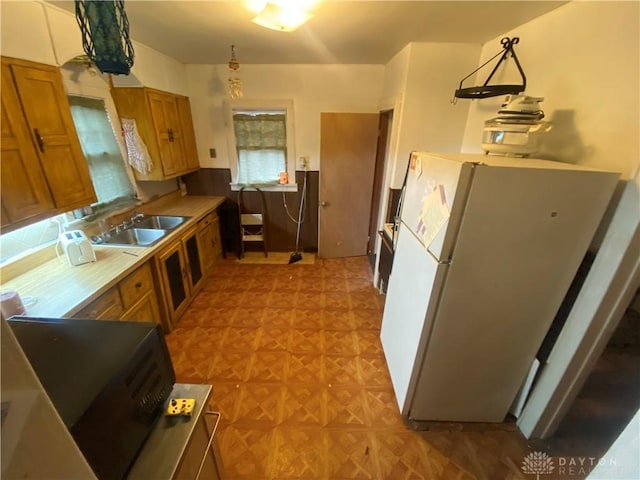 kitchen featuring white refrigerator, sink, light parquet floors, and decorative light fixtures