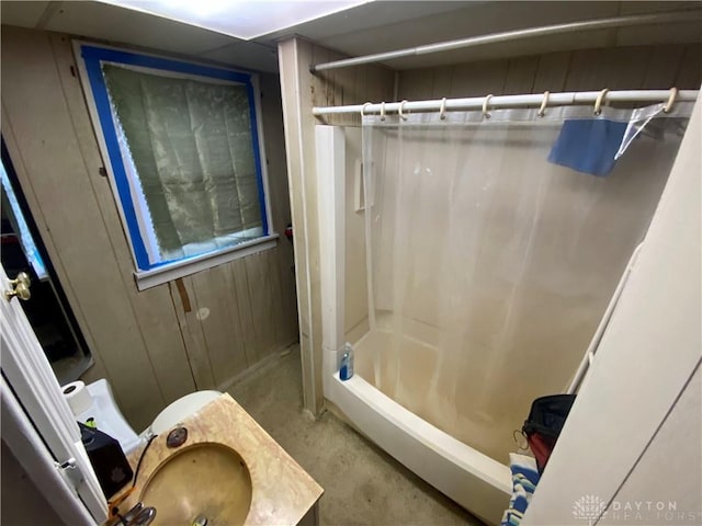 bathroom featuring shower / bath combination with curtain, concrete floors, and wood walls