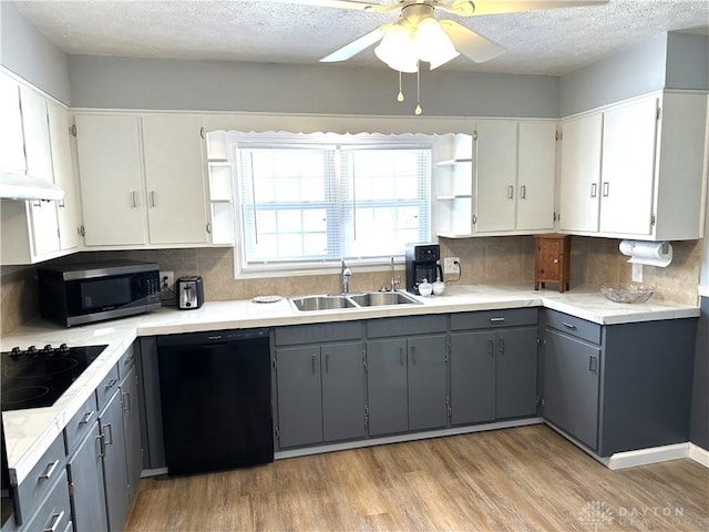 kitchen with sink, gray cabinets, black appliances, and light wood-type flooring